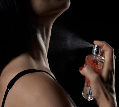 caucasian woman holds a glass transparent bottle with perfume in her hand and presses the spray, close up