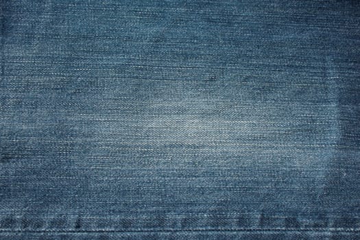 Fragment of blue frayed denim jeans background