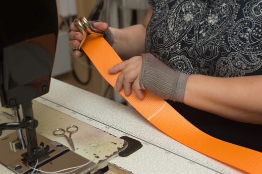 Industrial sewing machine sews a webbing sling. Manufacture of textile slings and tie straps