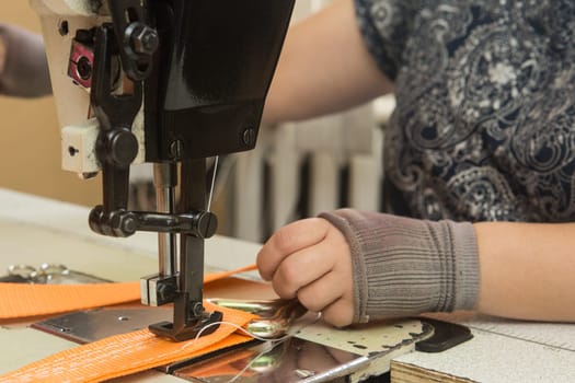 Industrial sewing machine sews a webbing sling. Manufacture of textile slings and tie straps