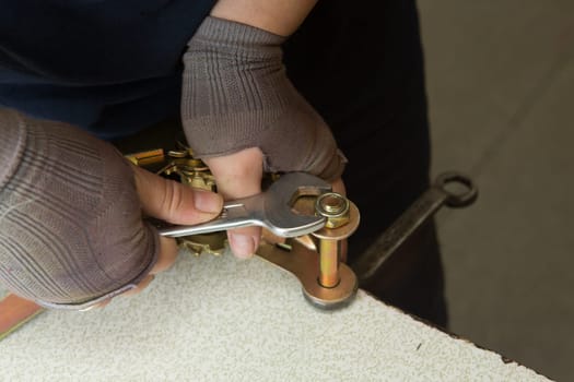 Woman mechanic working in metal workshop using clamps, screws, and spanner.