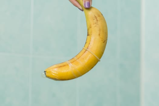 Condom and banana on a blue background close-up.
