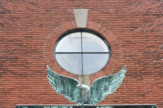 a Eagle with outstretched wings in front of a red brick wall