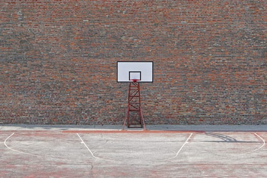 Basketball court with one hoop in front of brick wall