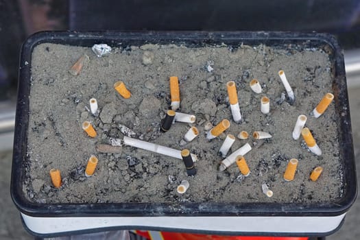 Ashtray with cigarette buts in sand