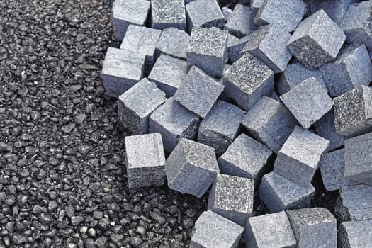 Big bunch of cobblestone bricks at new asphalt