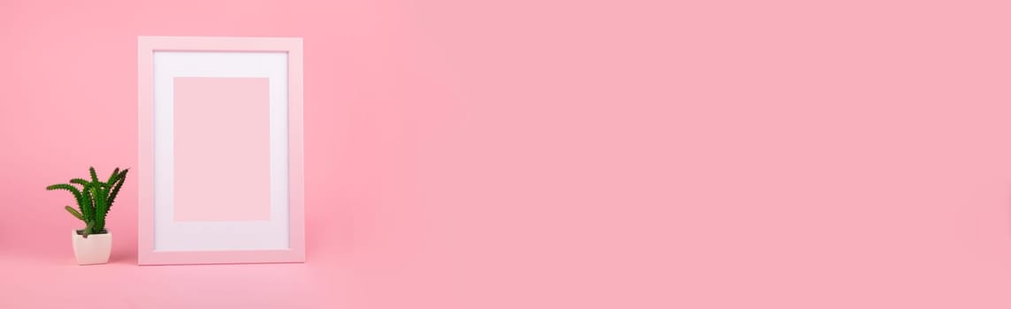 Panorama from decorative pink wooden picture frame and cactus over pink background
