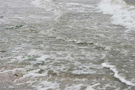 Waves with white crests inundate the sandy beach