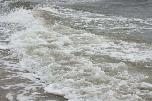 Waves with white crests inundate the sandy beach