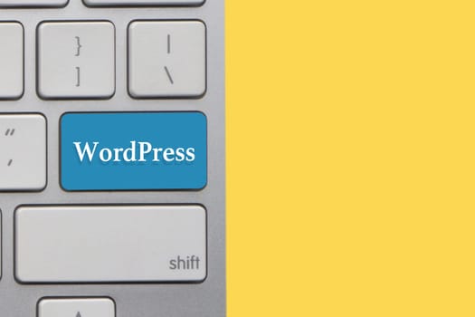 WORDPRESS text on keyboard over yellow background. Business and technology concept