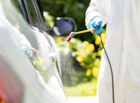 Close up chemical alcohol spray cleaning on door handle to disinfect and decontaminate coronavirus covid-19 by specialist cleaner wear personal protective equipment PPE. New normal Hygiene concept.