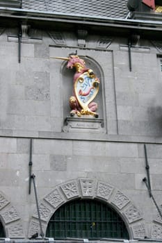 Crest with Unicorn, grey stone wall in the background .