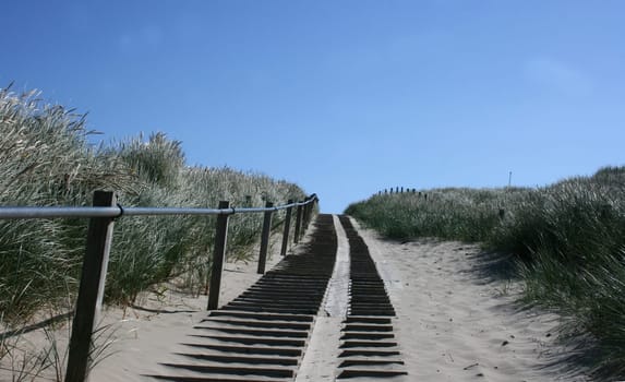 A steep climb up a dune, blue sky in the background