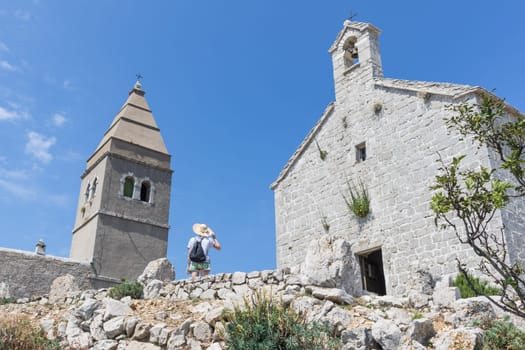 Female traveler sightseeing in an ancient costal village of Lubenice on the island of Cres, Croatia.