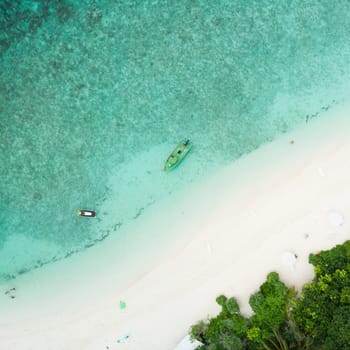 Aerial drone view of picture perfect beach and turquoise lagoon on small tropical island on Maldives.