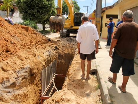 eunapolis, bahia / brazil - november 17, 2010: backhoe machine works on the implementation of a sewage network on a street in the city of Eunapolis, in the south of Bahia..