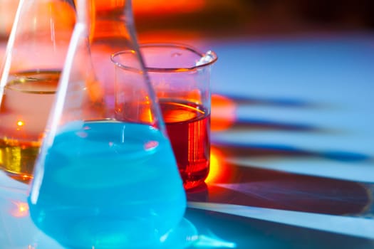 Backlit laboratory test flask containing colorful liquids.