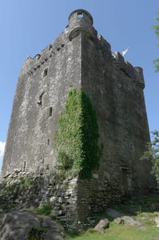 Sun and shade contrast across the imposing vertical exterior walls of moy castle near lochbuie on the isle of mull. Blue skies and strong composition