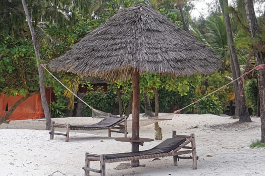 Beach bed under palm parasol at white sand