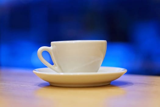 Porcelain coffee cup at table over dark blue background
