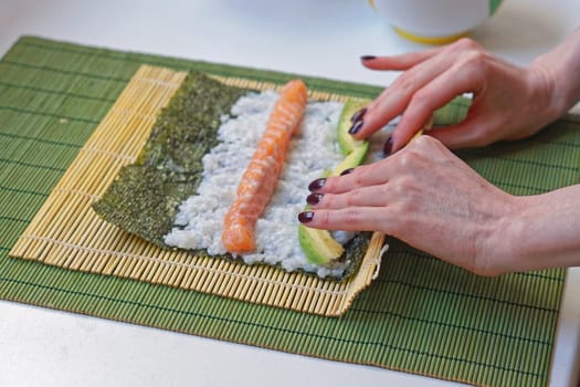 Woman rolling sushi with bamboo mat