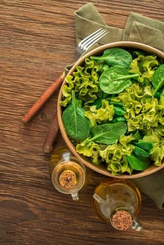 Healthy green salad with dressing on wooden table background. Healthy diet food.