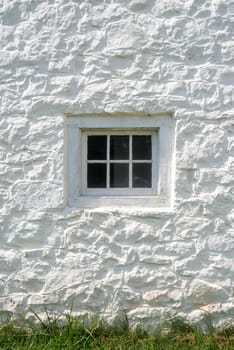Whitewashed stone gleams in natural light with antique glass window and window frame made with wooden dowels.