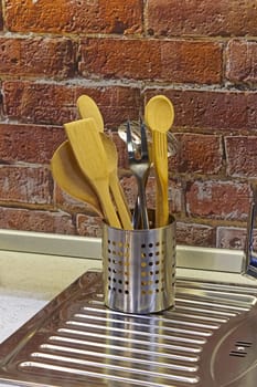 Can of kitchen utensils at stainless steel sink