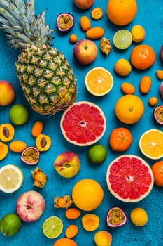 Flat lay layout of summer and citrus fruits on blue background. Healthy eating concept.