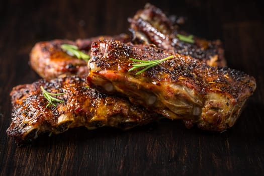 Grilled pork spare ribs with rosemary on wooden background. Barbecue food concept.