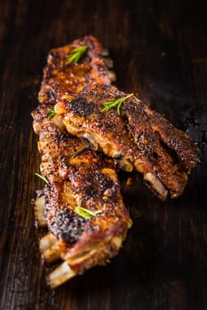 Grilled pork spare ribs with rosemary on wooden background. Barbecue food concept.