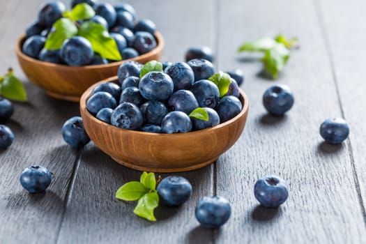 Fresh organic blueberry in bowl on wooden background. Healthy food concept, juicy wild forest berries.