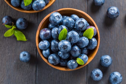 Fresh organic blueberry in bowl on wooden background. Healthy food concept, juicy wild forest berries.