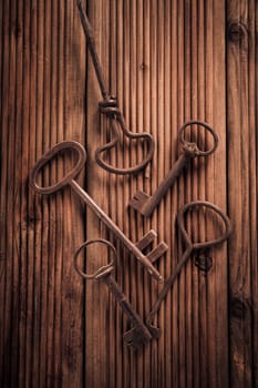 Assortment of vintage keys on wooden background. Top view.