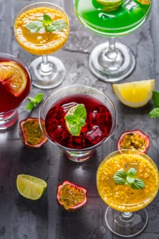 Assortment of different cocktails with fresh fruits, ice and mint on black background.
