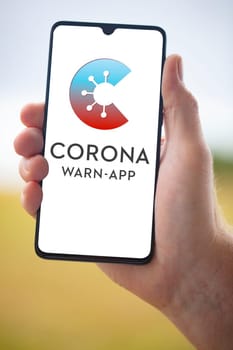 WETZLAR GERMANY 2020-08-26, CORONA APP Official German Corona Warning App on mobile phone held by hand on blurry background