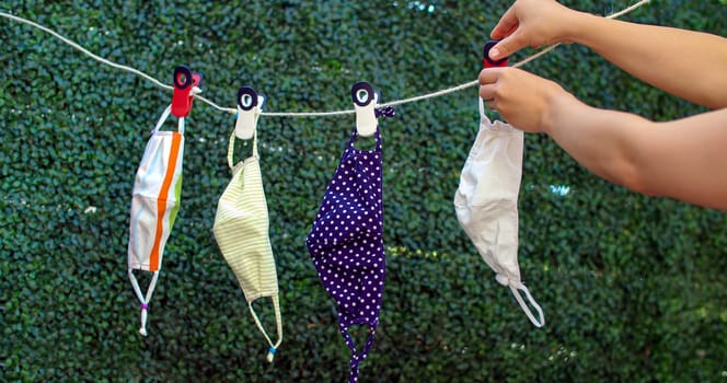 A person Drying outside reusable family face masks, hang on a clothesline nylon rope with clothespins.