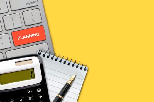 Flat lay, top view office table desk. PLANNING text with pen, calculator, notepad and keyboard on the yellow background. Business Finance, Education and Copy Space concept