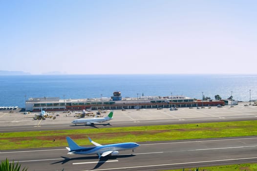 Airplane taking off runway of Madeira International Airport, sunny ocean view in background, Funchal, Portugal
