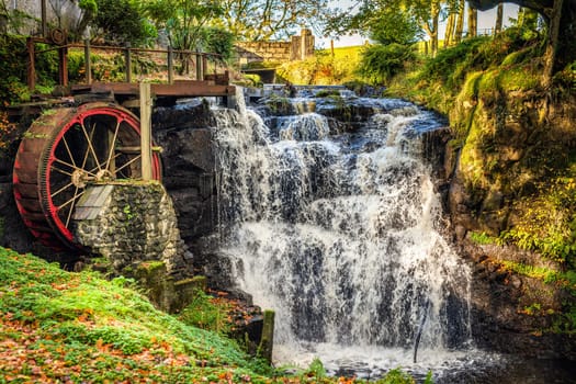 Vintage red waterwheel with waterfall in autumn colours in Glenariff Forest Park, Count Antrim, Northern Ireland