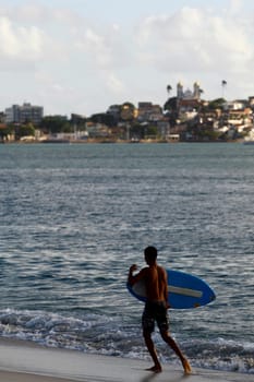 salvador, bahia / brazil - august 12, 2015: young man is seen surfing with a piece of wood on Ribeira beach in the city of Salvador.