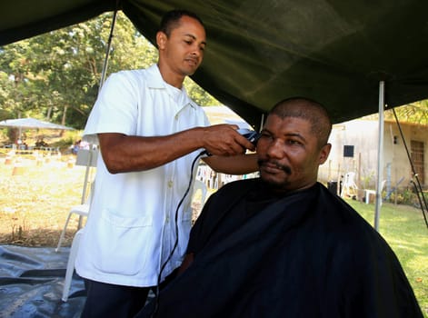 salvador, bahia / brazil - november 4, 2015: barber from the navy of Brazil cuts a person's hair during social action on Ilha de Mare, in the city of Salvador.