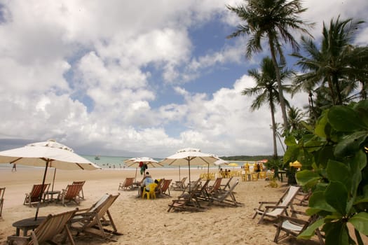 porto Seguro, bahia / brazil - january 7, 2011: people are seen sitting next to chairs on the beach of Trancoso in the city of Porto Seguro, in the south of Bahia.