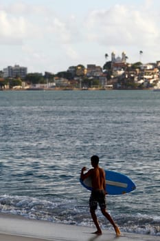 salvador, bahia / brazil - august 12, 2015: young man is seen surfing with a piece of wood on Ribeira beach in the city of Salvador.