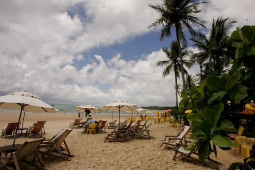 porto Seguro, bahia / brazil - january 7, 2011: people are seen sitting next to chairs on the beach of Trancoso in the city of Porto Seguro, in the south of Bahia.