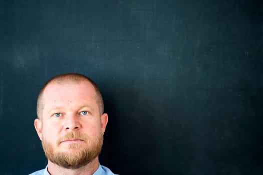 Handsome businessman standing at the empty blackboard with copy space.