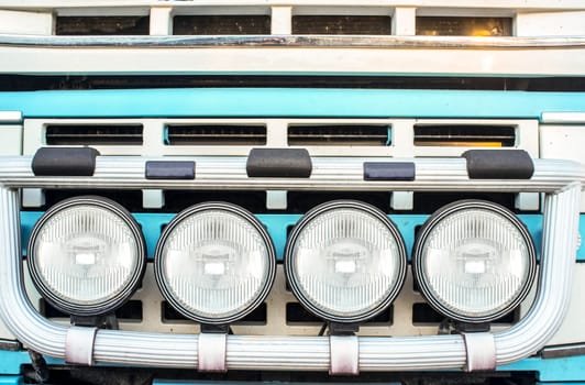 Tractor truck radiator grid protected with bumper-mounted offroad spotlights. Blue arctic painted