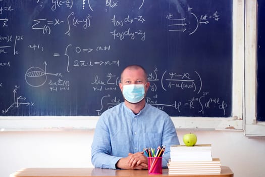 Male teacher with mask teaching math lesson at school. Social distanting and classroom safety during coronavirus epidemic