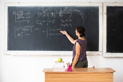 Female teacher with mask teaching math lesson at school. Social distanting and classroom safety during coronavirus epidemic