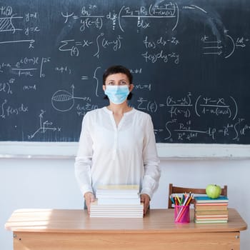Teacher with face mask welcoming children back at school after lockdown. Back to school during COVID-19 pandemic.